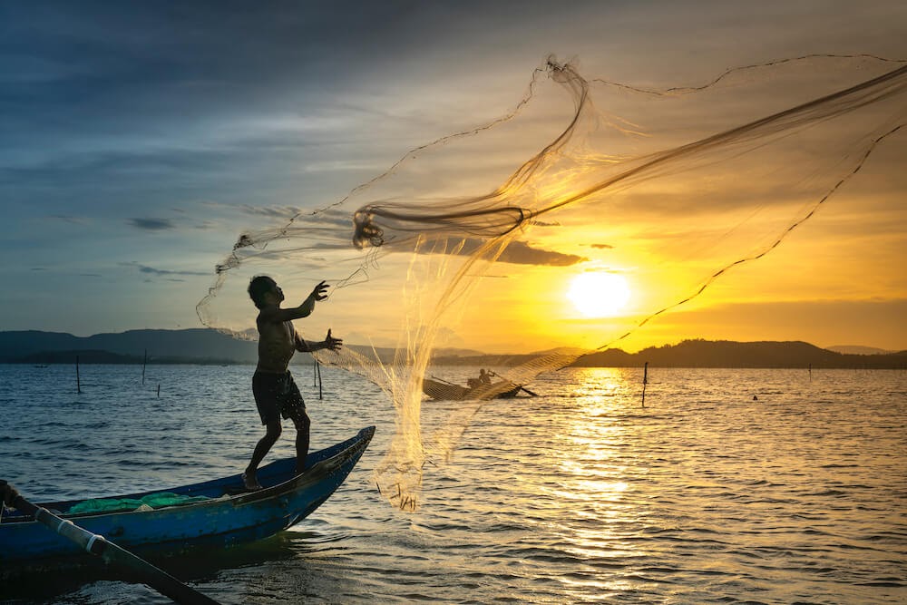 person-throwing-fish-net-while-standing-on-boat feature image for I don't want to work.jpg