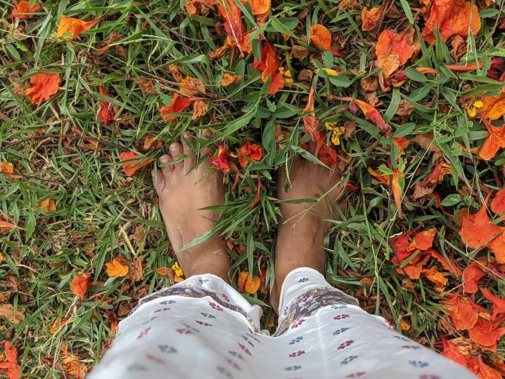 writer with her feet on the ground patted with flowers 5 years of on my canvas personal growth and travel blog